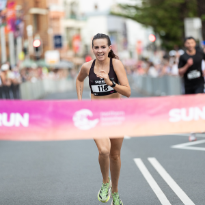 female winner runs across finish line at Sun Run
